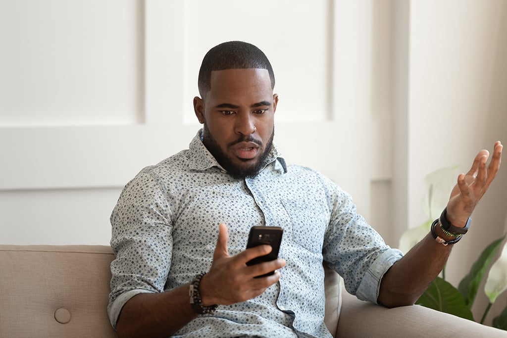 Young man looks at his phone, wondering how to deal with disorganized attachment in a partner.