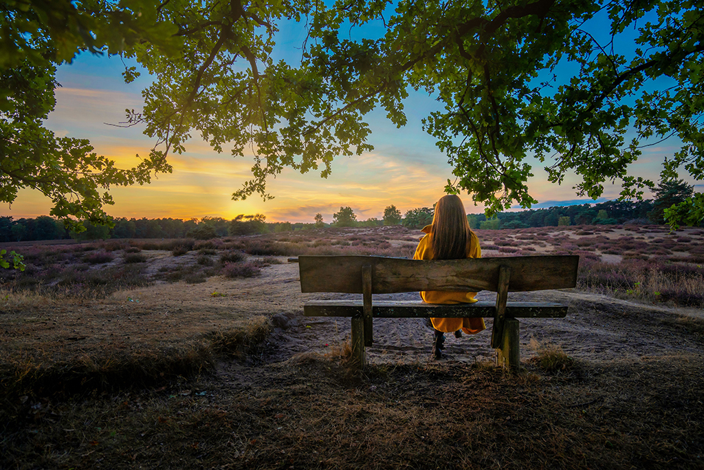 woman on a bench watches the sun set at a women’s mental health retreat